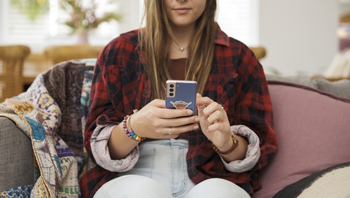 Person sitting on a couch scrolling on a mobile phone