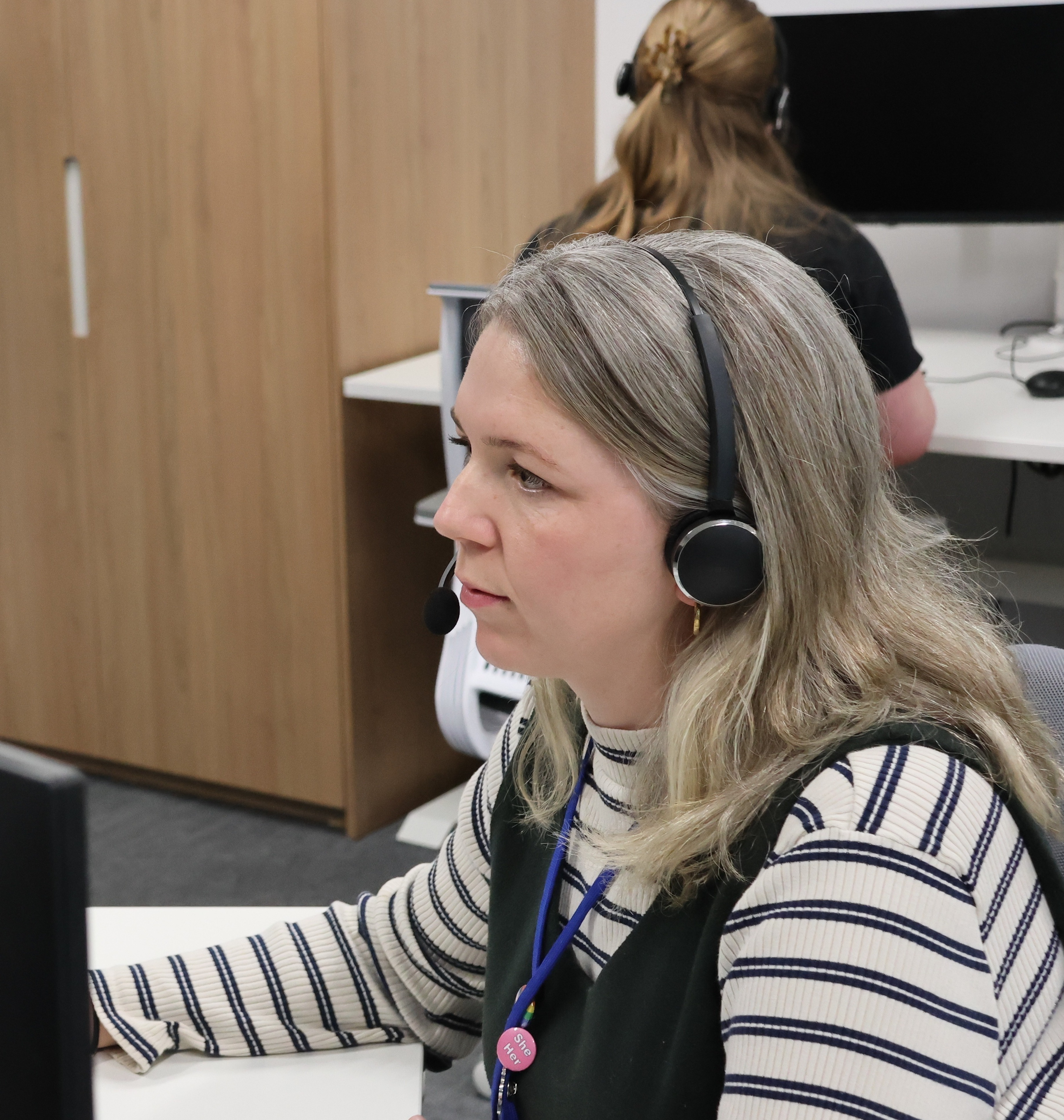 Laura at the computer with a headset on